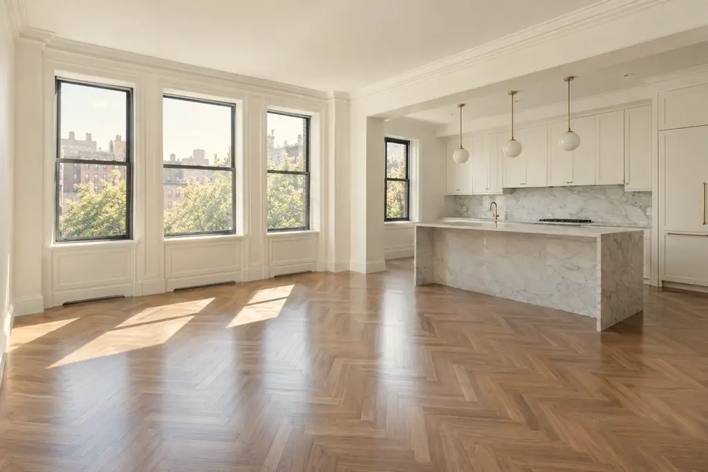 An empty, freshly cleaned apartment with gleaming oak floors, an open white kitchen and a marble island, ready to list